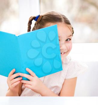 Cute girl is reading book - school, education concept