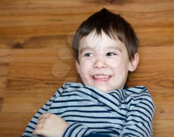 Portrait of happy joyful laughing beautiful little boy on woden background
