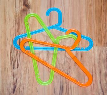 Set of colorful plastic clothes hangers on wooden background