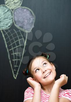 Cute happy girl is eating ice-cream. On a black background