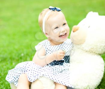 Little cute girl is playing her teddy bear, outdoors