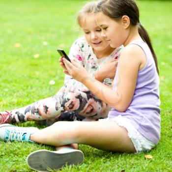 Two young girl with tablet at the park