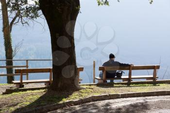 Lonely man sitting on bench with beautiful view of the mountains. The Park and the forest outside the city.