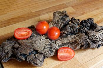 Red tomatoes on wood driftwood. Abstract still life.