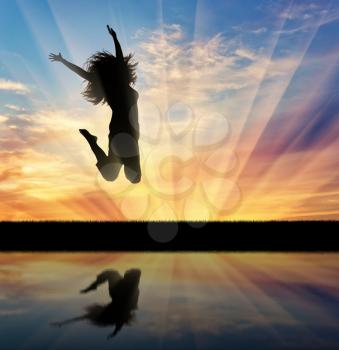 Happiness success woman. Happy woman jumping at sunset and its reflection