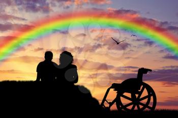 Disabled concept. A disabled person and carer at sunset rainbow