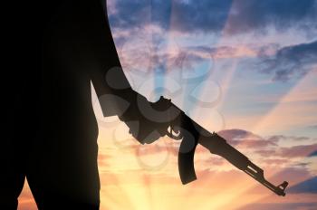 Terrorist concept. Silhouette of a terrorist with a weapon in hand at sunset
