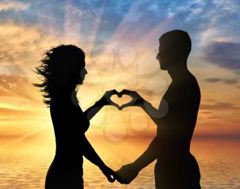 Love and feelings. Loving couple showing heart symbol on hands against sea sunset