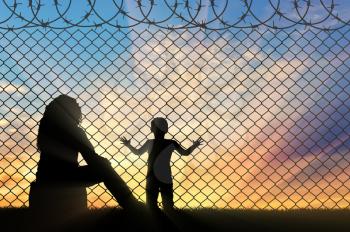 Refugees concept. Mother with a small child refugees, near the fence of barbed wire