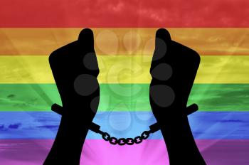 Discrimination against gay rights. Silhouette gay hands in handcuffs on the background of the rainbow
