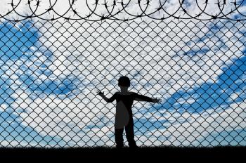 Refugee children concept. Child refugee, near the fence of barbed wire
