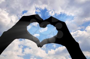 Love and feelings. Hands show a gesture of heart on the background of the sky