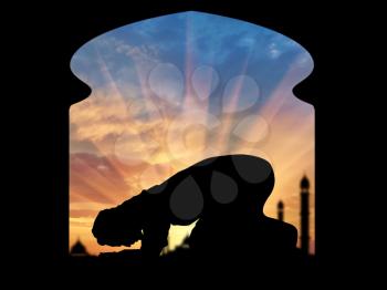 Islamic religion. Muslim praying in a room on the background of a mosque at sunset