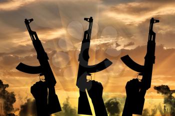 Terrorists concept. Weapons in the hands of terrorists, against the background of a sunset in the smoke