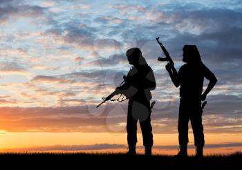 Terrorism and conflict. Two armed terrorists at sunset