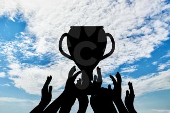 Cup concept. Silhouette of a hand holding the championship trophy against the sky