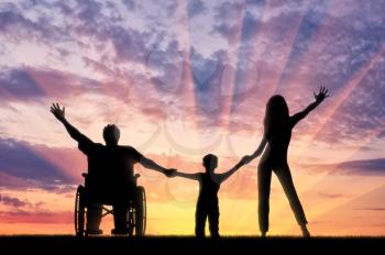 Happy disabled person in wheelchair with his family holding hands on sunset. Concept happy disabled and family