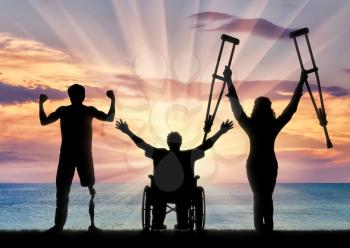 Three happy disabled with prosthesis and crutches and in wheelchair near sea. Concept happy disabled
