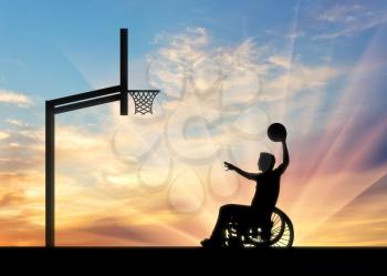 Disabled sportsman person in wheelchair rolls ball into basket sunset. Concept sport and willpower