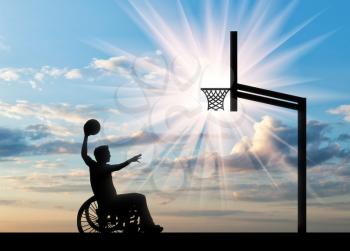 Disabled sportsman in wheelchair rolls ball into basket day. Concept sport and willpower