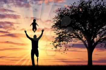 Disabled person with prosthetic leg with small child playing near tree sunset background. Concept disabled and family