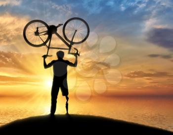 Disabled person with prosthetic leg standing on hill and holding bicycle over his head sea. Concept disabled and sport