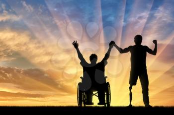 Disabled person with prosthetic leg and disabled in wheelchair holding hands on sunset. Concept disabled
