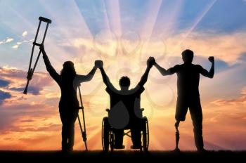 Disabled people on crutches and in wheelchair and with prosthetic leg to stand on sunset and holding hands. Concept happy disabled