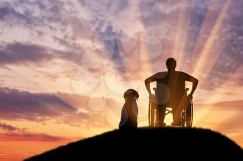 Concept of disability and old age. Silhouette of disabled person in a wheelchair with his dog at sunset