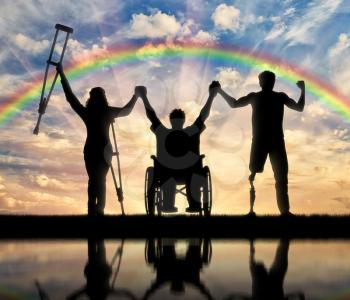 Invalids on crutches and in wheelchair and prosthesis in foot standing on rainbow background and holding hands. Concept happy disabled
