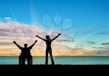  Concept of disability and disease. Silhouette happy disability and caregiver at the sea sunset