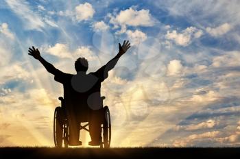 Concept of disability and disease. Silhouette happy disabled person in a wheelchair at sunset 