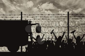 Concept of the refugees. Silhouette of humanitarian assistance to refugees near the fence with barbed wire