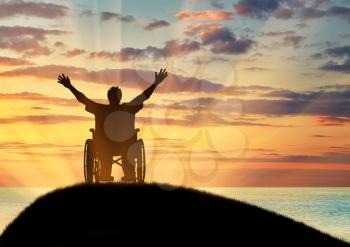 Concept of disability and disease. Silhouette happy disabled person in a wheelchair and sea sunset