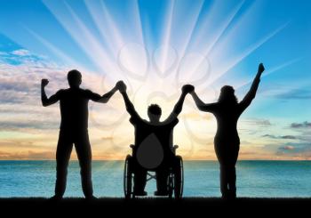 Disabled in wheelchair and healthy people holding hands on sea day. Concept happy disabled