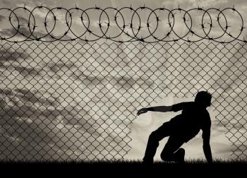 Concept of the refugees. Silhouette of refugees crossed the border illegally through the hole in the fence