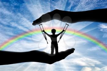 Disabled child standing with crutches in hand on background rainbow day. Concept children with disabilities