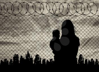 Concept of the refugees. Silhouette refugee mother with a baby in the background of the fence and the city at sunset