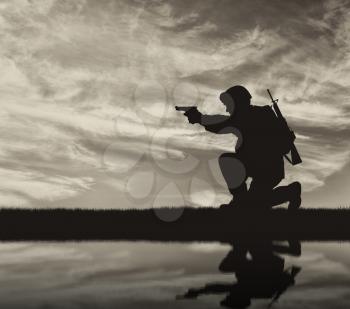 Silhouette of a terrorist with a weapon against a background of a sunset and reflection