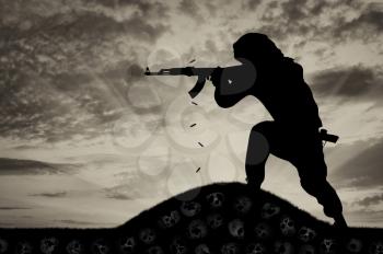 Concept of a terrorist. Silhouette of a terrorist attack gunman with a rifle and the land of skulls
