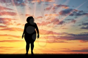 Fat woman standing on sunset background. Overweight concept