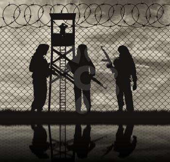 Concept of terrorism. Silhouette terrorists near the border fence in the background at sunset and reflection