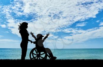 Happy boy in a wheelchair and a nurse at the sea day. Happy disabled child concept