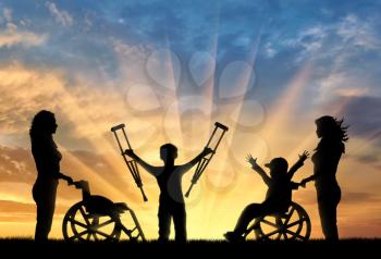 Happy boy in wheelchair and boy standing with crutches disabled person and nurses sunset. Happy disabled child concept