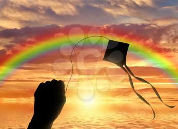 Hand holding kite near sea and sun sets for horizon. Vacation concept