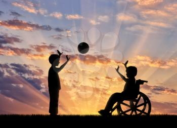 Happy boy in a wheelchair playing with a boy in ball sunset. Concept happy child disabled