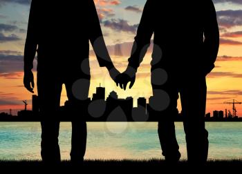 Concept of gay people. Silhouette happy gay men holding hands against the evening sea sunset and the city
