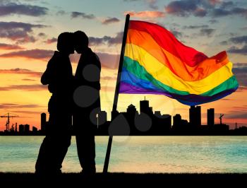 Concept of gay people. Silhouette happy gay men kissing on the background of the beautiful sea sunset with rainbow flag and the city in the distance