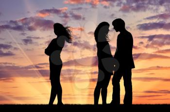 Concept of betrayal and treason. Silhouette of a lonely woman near loving couple at sunset