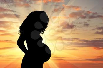 Concept of pregnancy. Silhouette of a pregnant woman at sunset